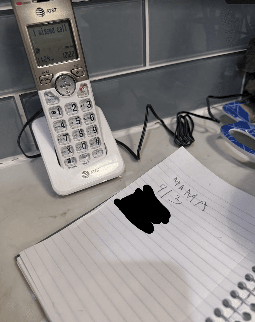 An AT&T cordless house phone beside a handwritten phone message.