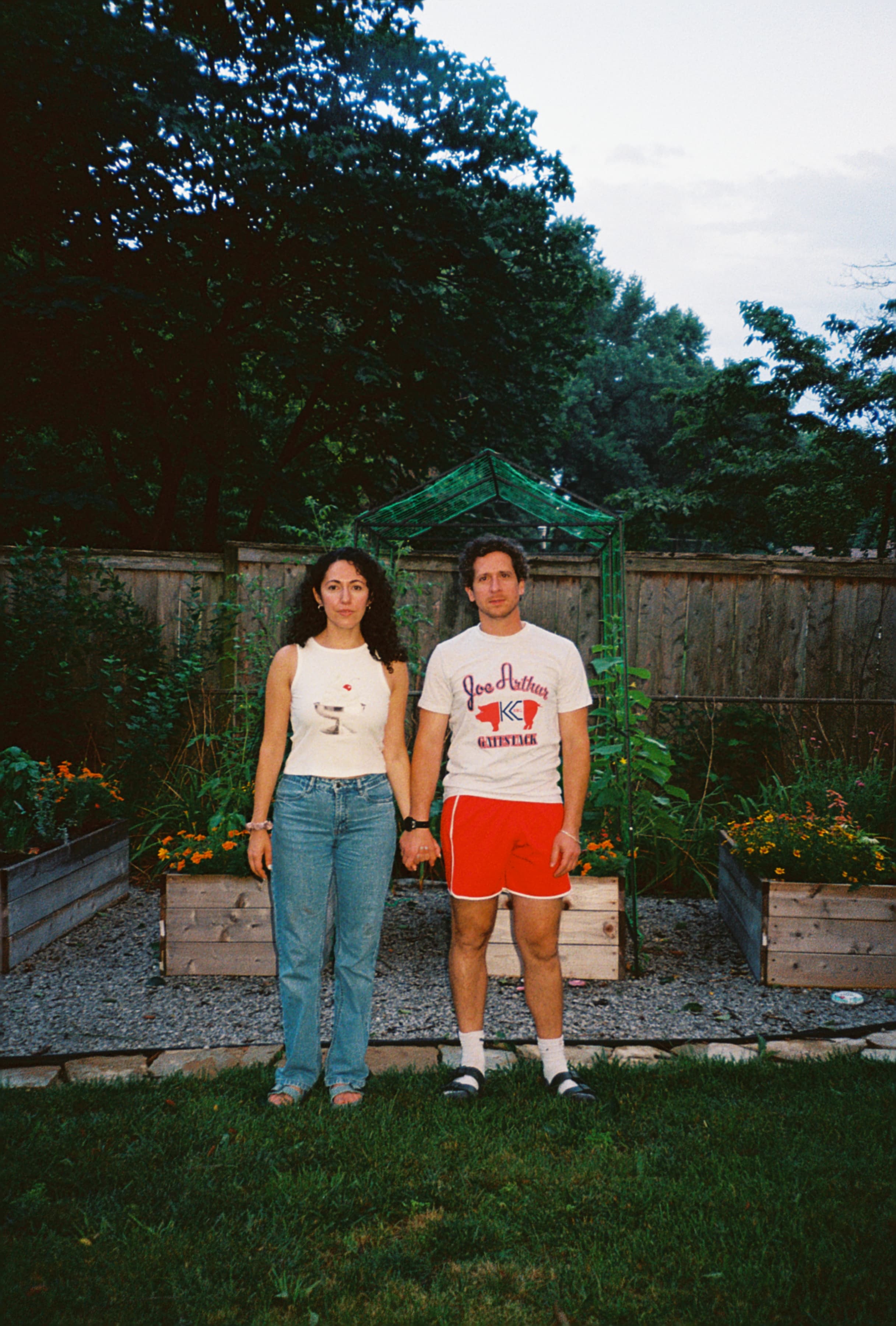 Julia and Shane standing hand in hand in a backyard garden